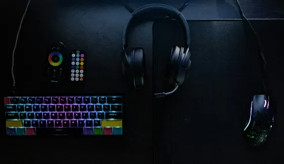 Teclado iluminado, diadema y mouse sobre un escritorio oscuro